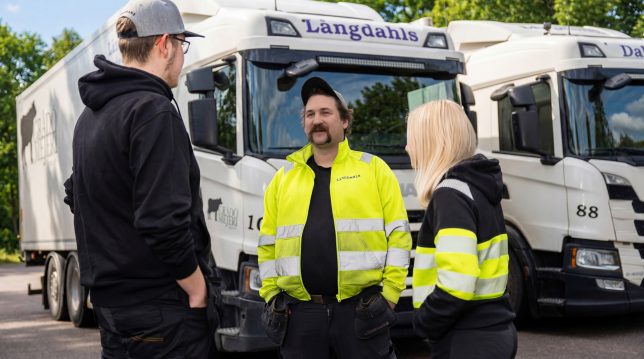 Chaufförer på Långdahls Åkeri står framför ett par lastbilar.